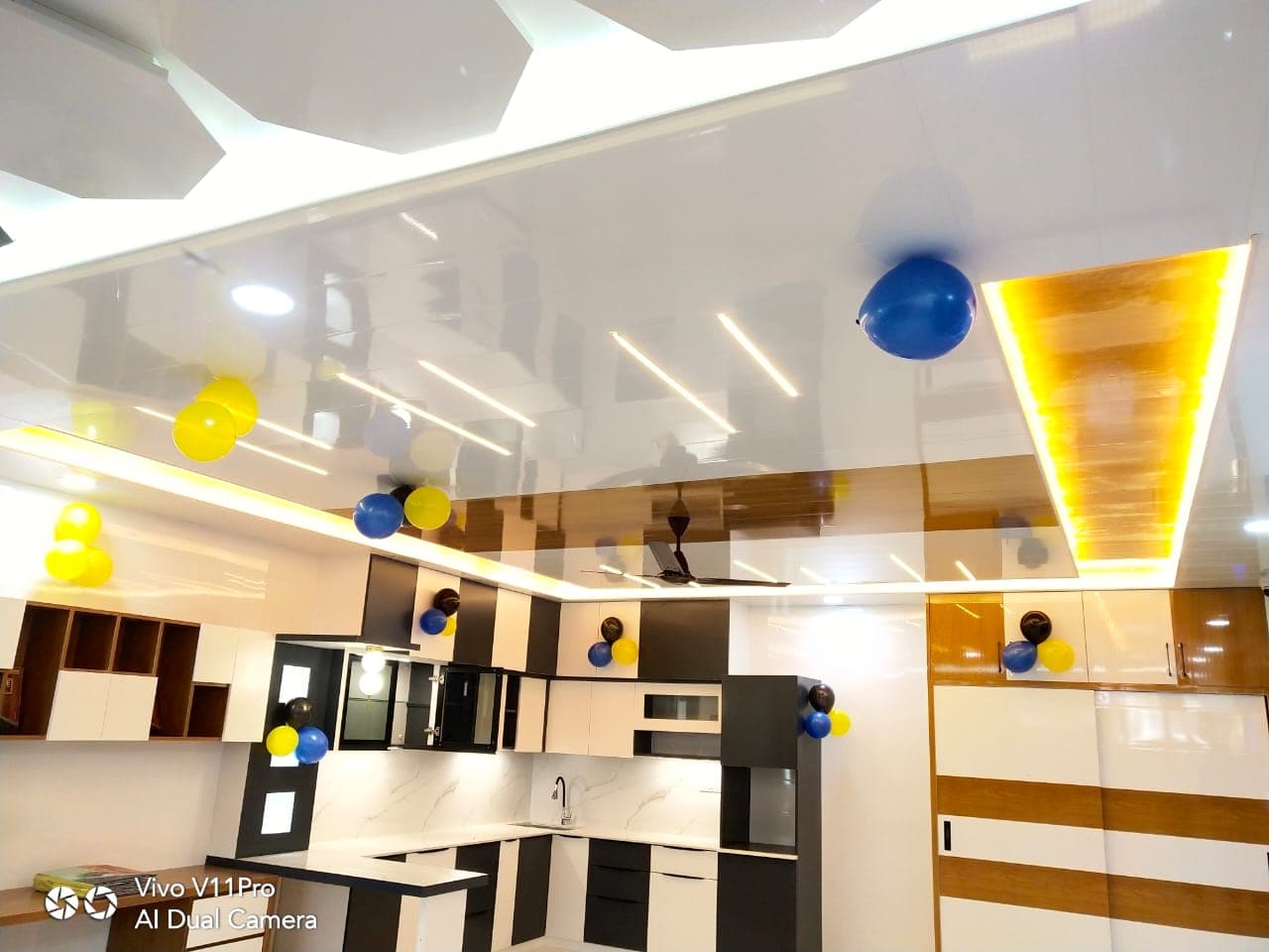 Black-and-white modular kitchen with a glossy multi-tier false ceiling.