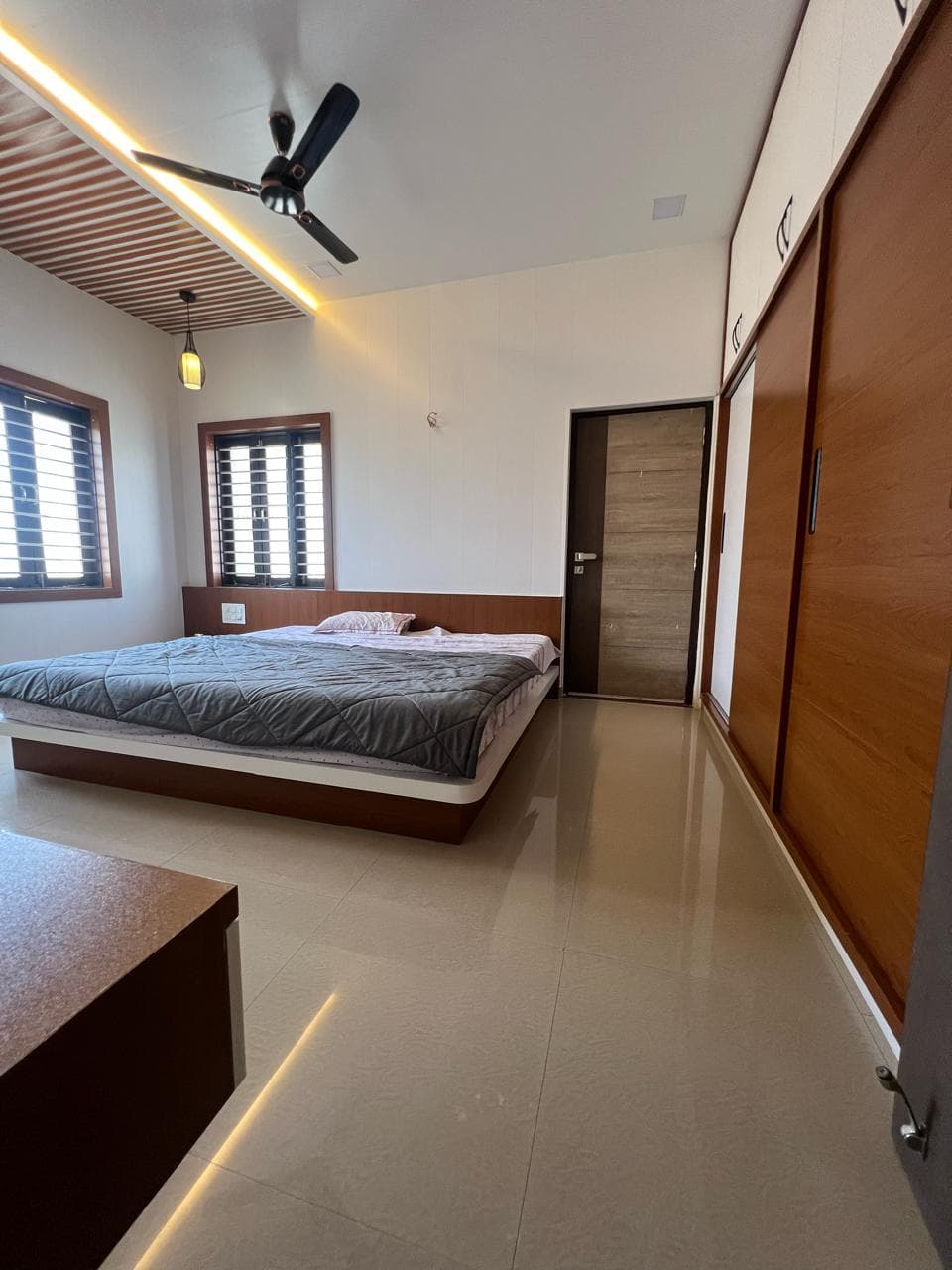 Bright bedroom with wood-slat ceiling cove and sliding wardrobes.