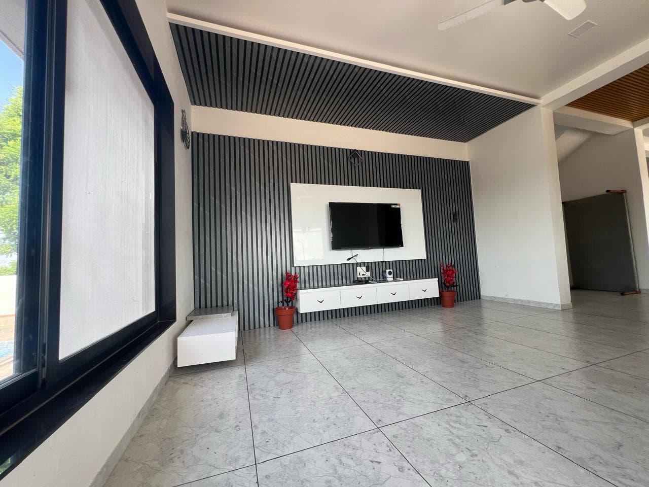 Fluted charcoal media wall with white floating console.
