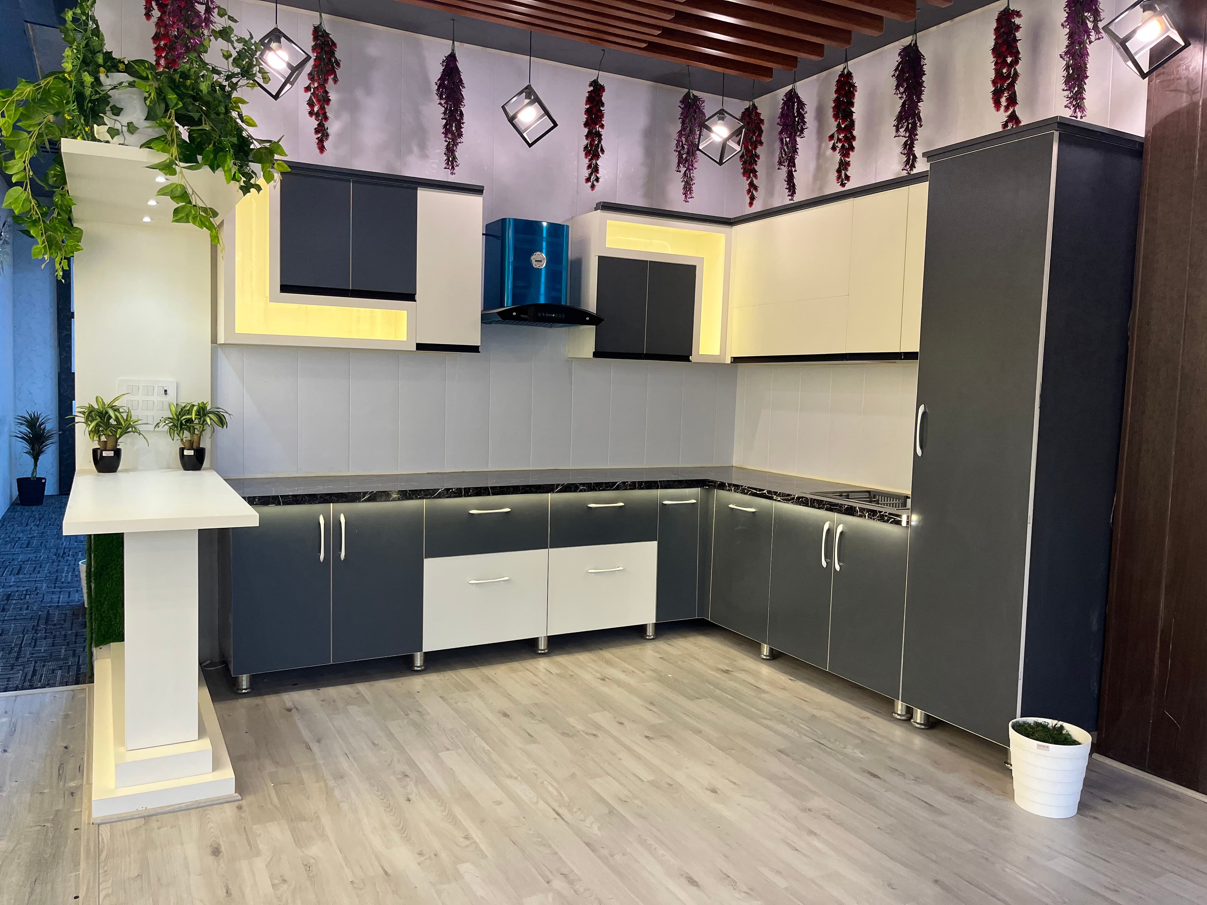 L-shaped charcoal and white RAVYA modular kitchen with LED accents.