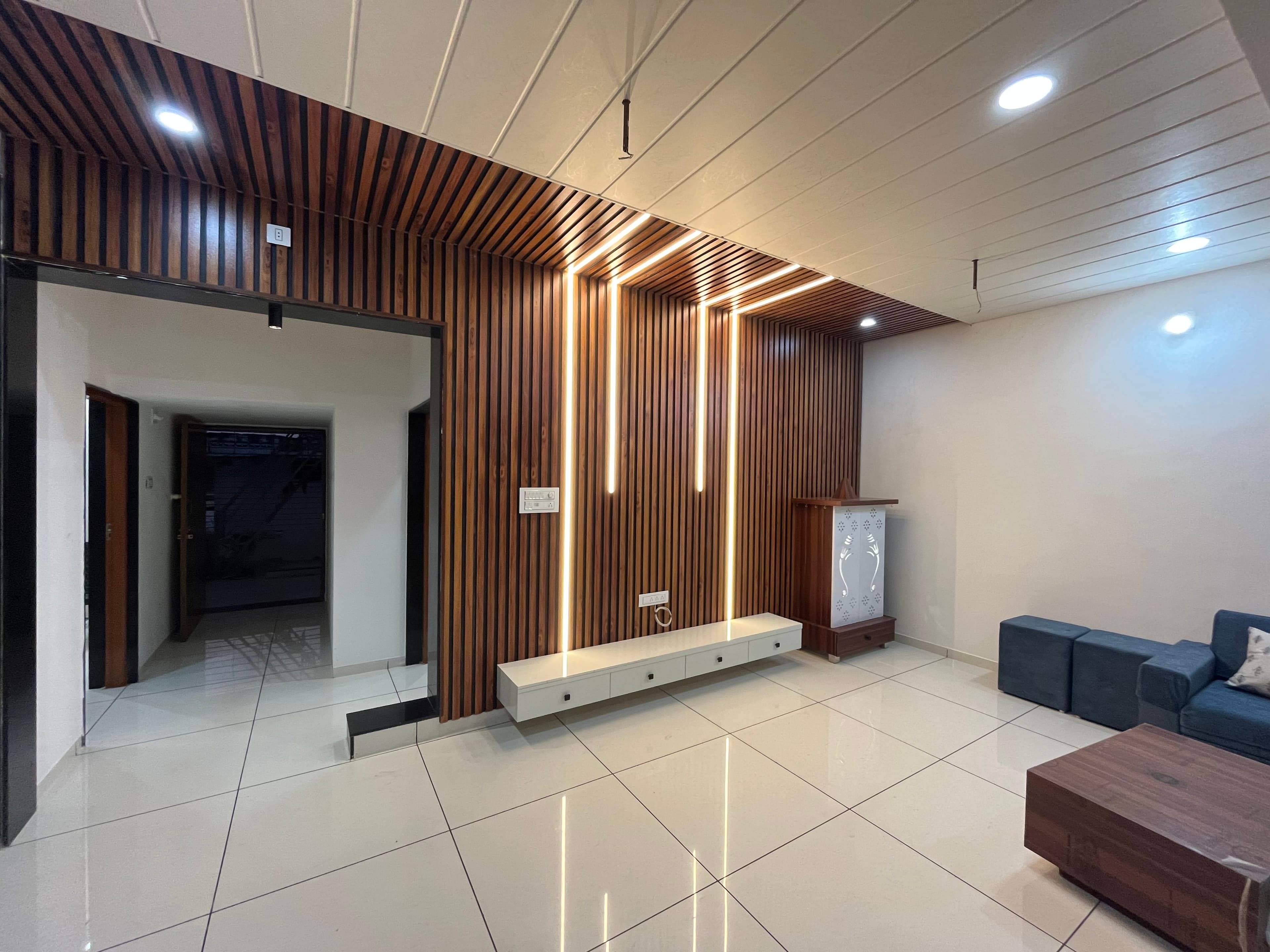 Living room with wood-slat feature wall, LED coves and a floating media console.