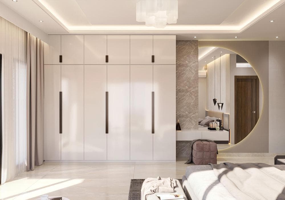 A floor-to-ceiling RAVYA PVC wardrobe with hinged fronts beside a lit circular mirror in a bedroom.